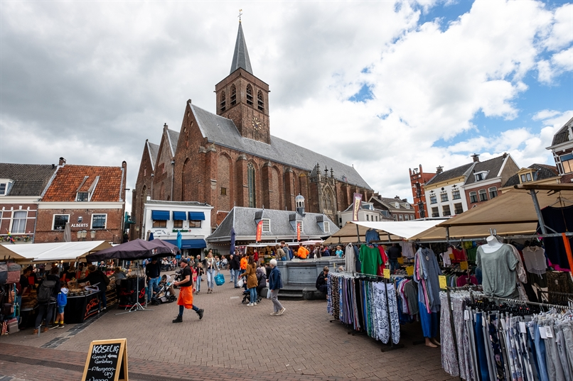   Mensen bezoeken de markt op de Hof, met op de achtergrond de Sint-Joriskerk. 